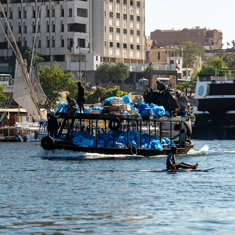 Garbage boat picking up trash from river boats