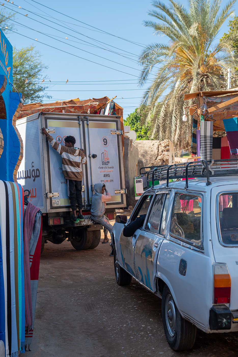 Two kids hanging from the back of a truck