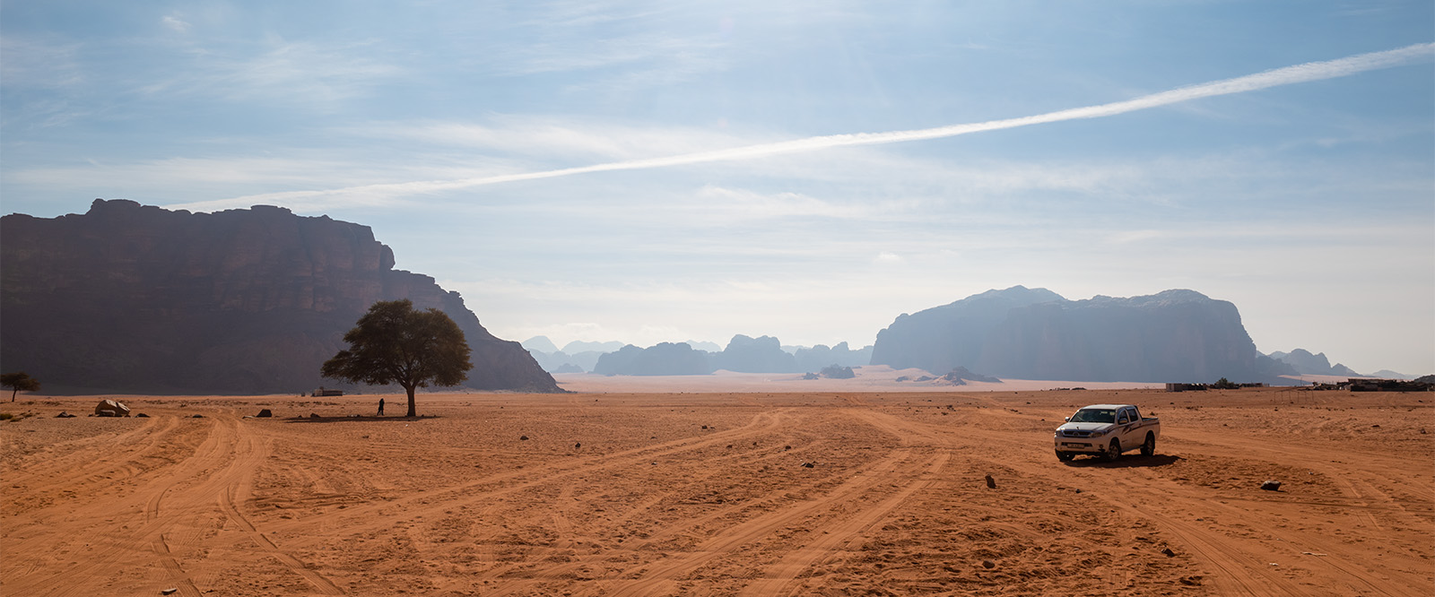 Panoramic of the Wadi Rum desert with a tree and truck